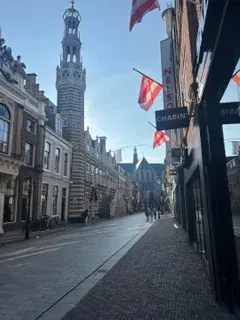 A shopping street hung with red and white flags leading to the Waagtoren in Alkmaar