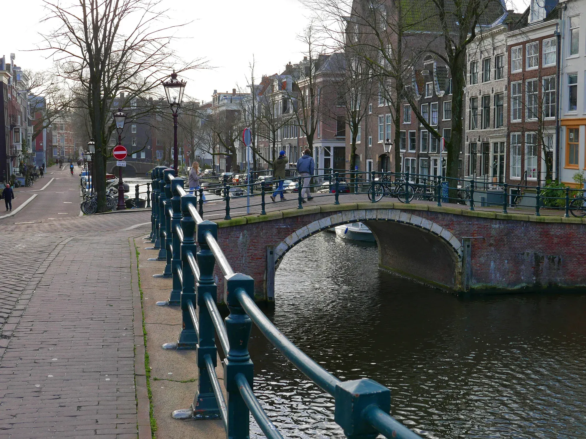 An old brick bridge over the Reguliersgracht reflected in still canal water