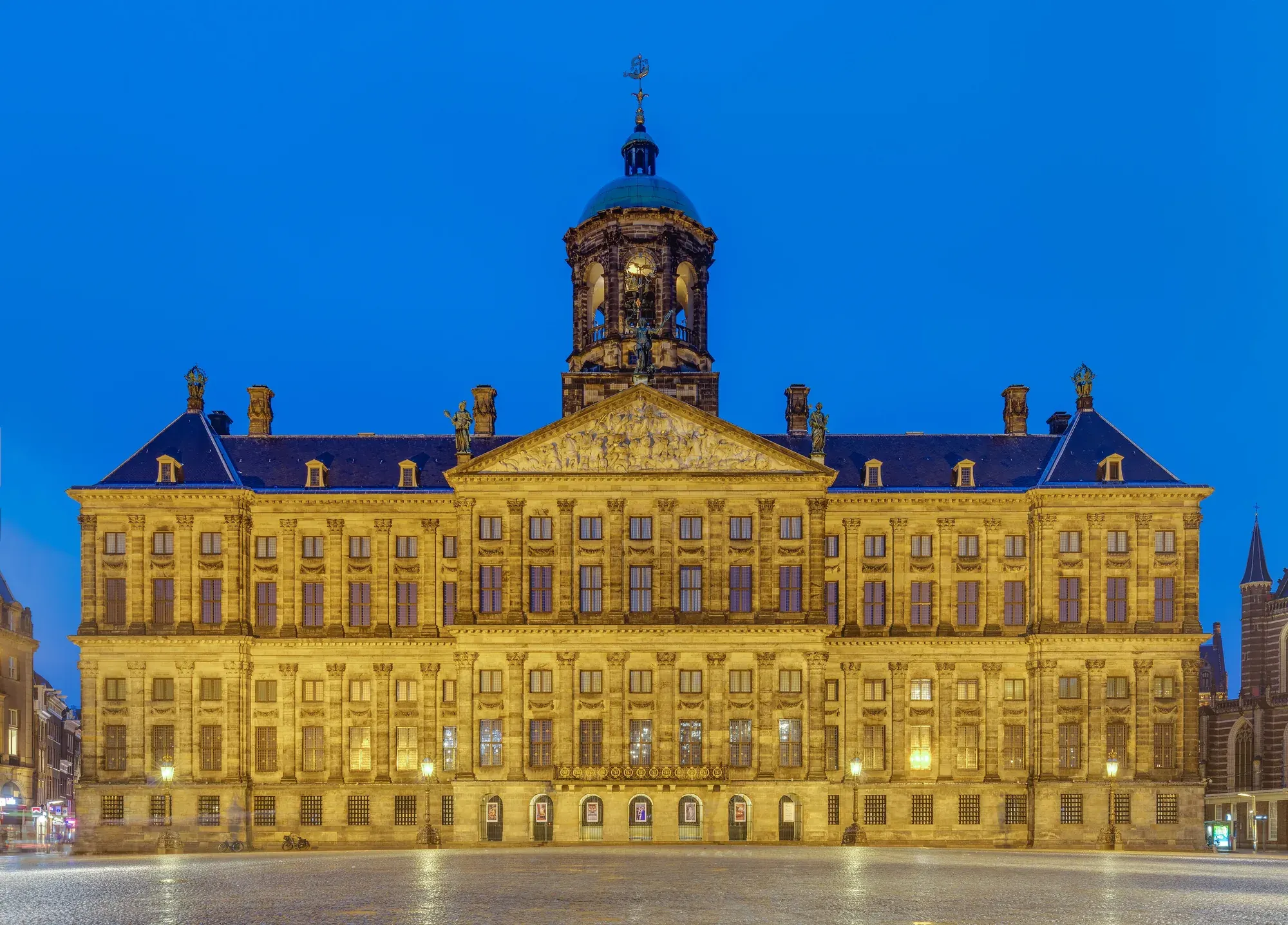 The Royal Palace on Dam Square lit up against a deep blue evening sky