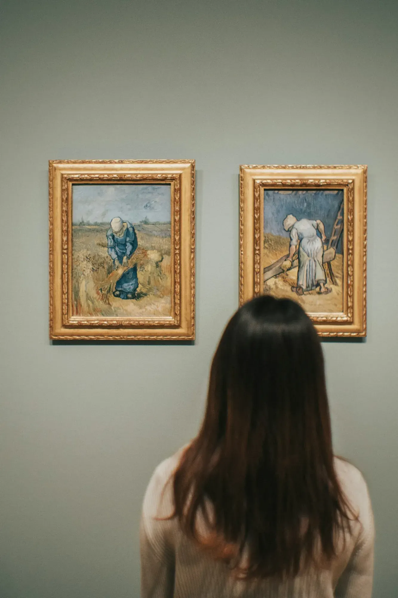 A visitor looking at two of Van Gogh's paintings after Millet's scenes of peasant work, Van Gogh Museum