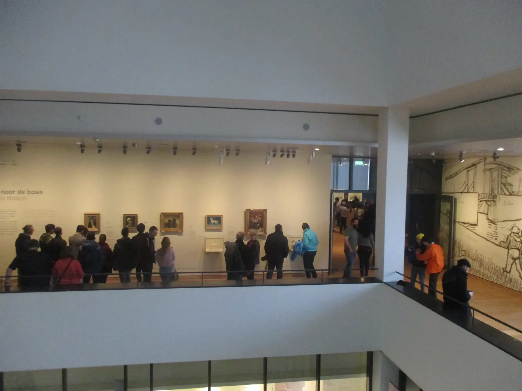 Visitors in an upper-floor gallery of the Van Gogh Museum, seen from across the open atrium