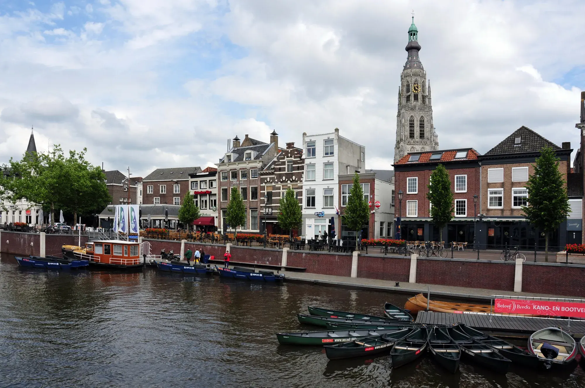 Boats along the quayside of Breda's harbour with the Grote Kerk tower above the rooftops
