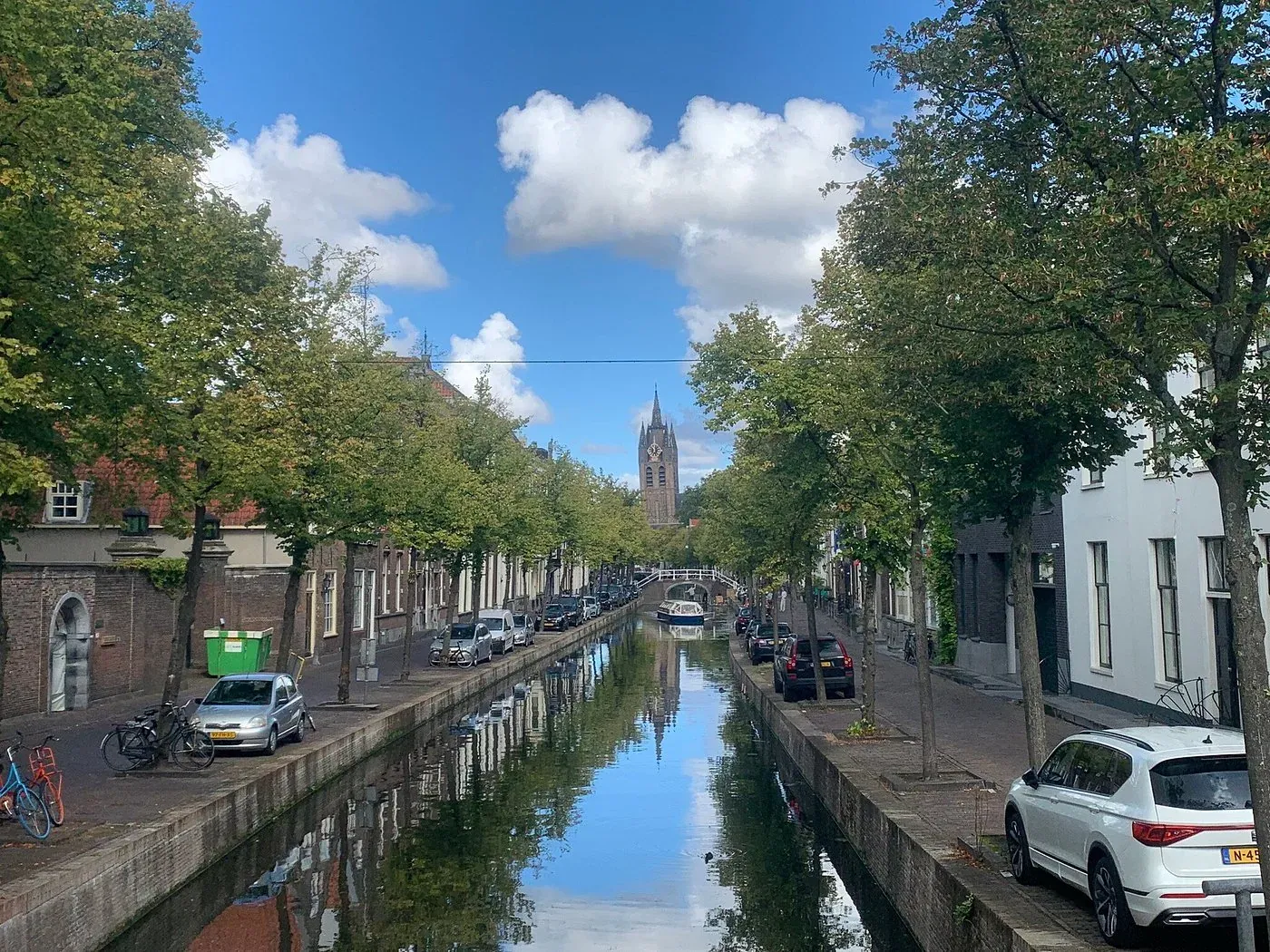 The Oude Delft canal in Delft, lined with trees and looking towards the leaning tower of the Oude Kerk