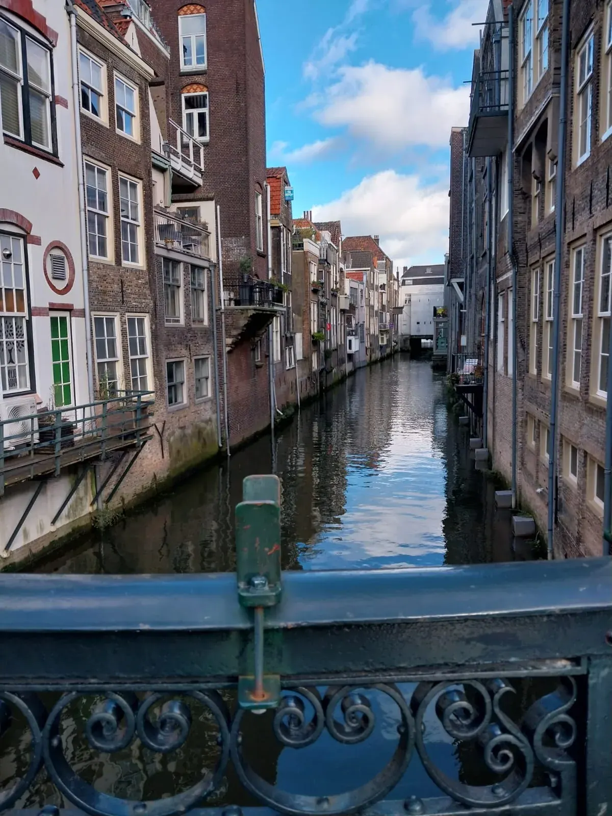 A Dordrecht canal seen over the ornate cast-iron railing of a bridge