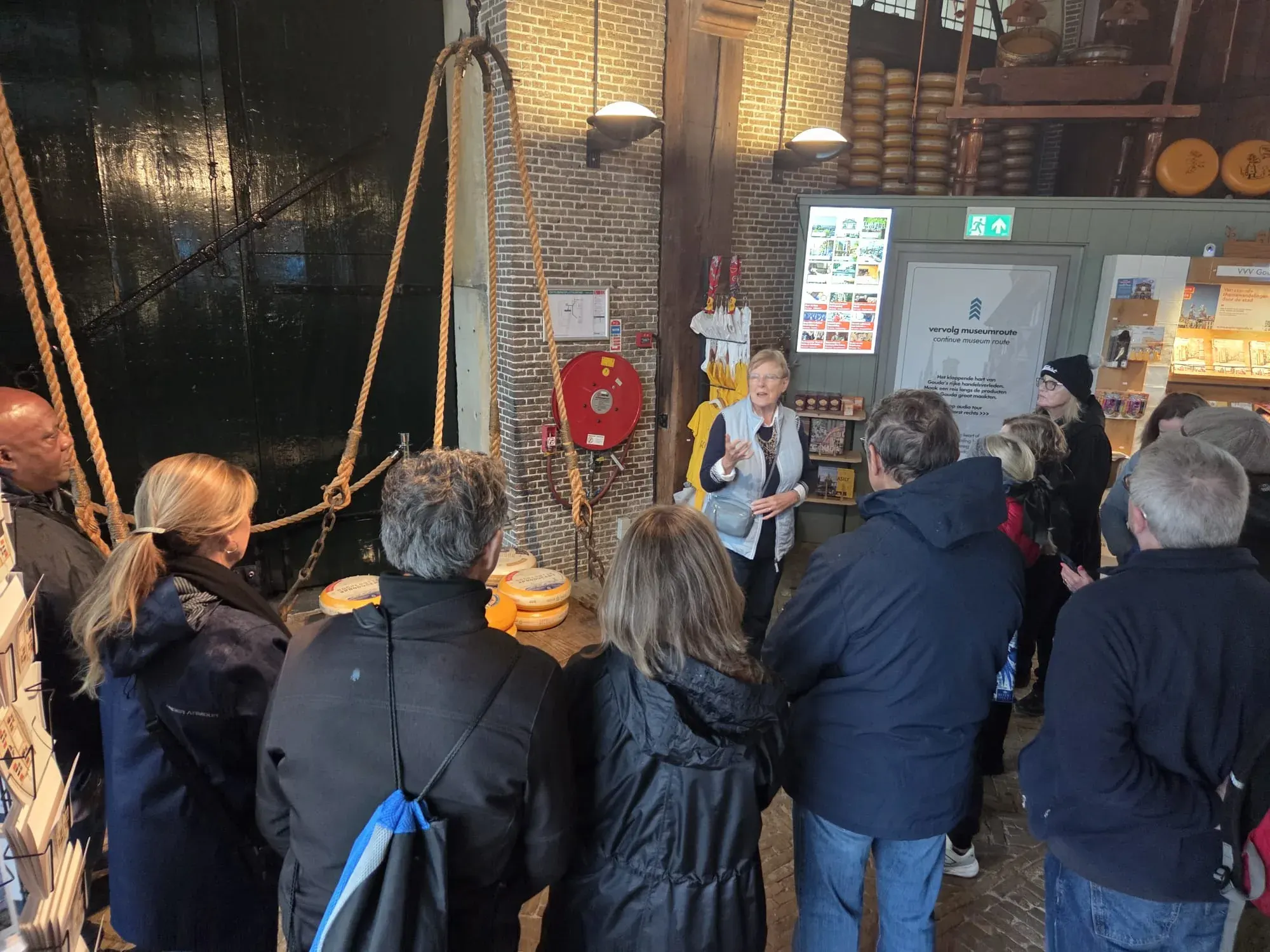 Eine Gruppe hört die Käsegeschichte unter den alten Waageseilen in der Goudse Waag, Gouda