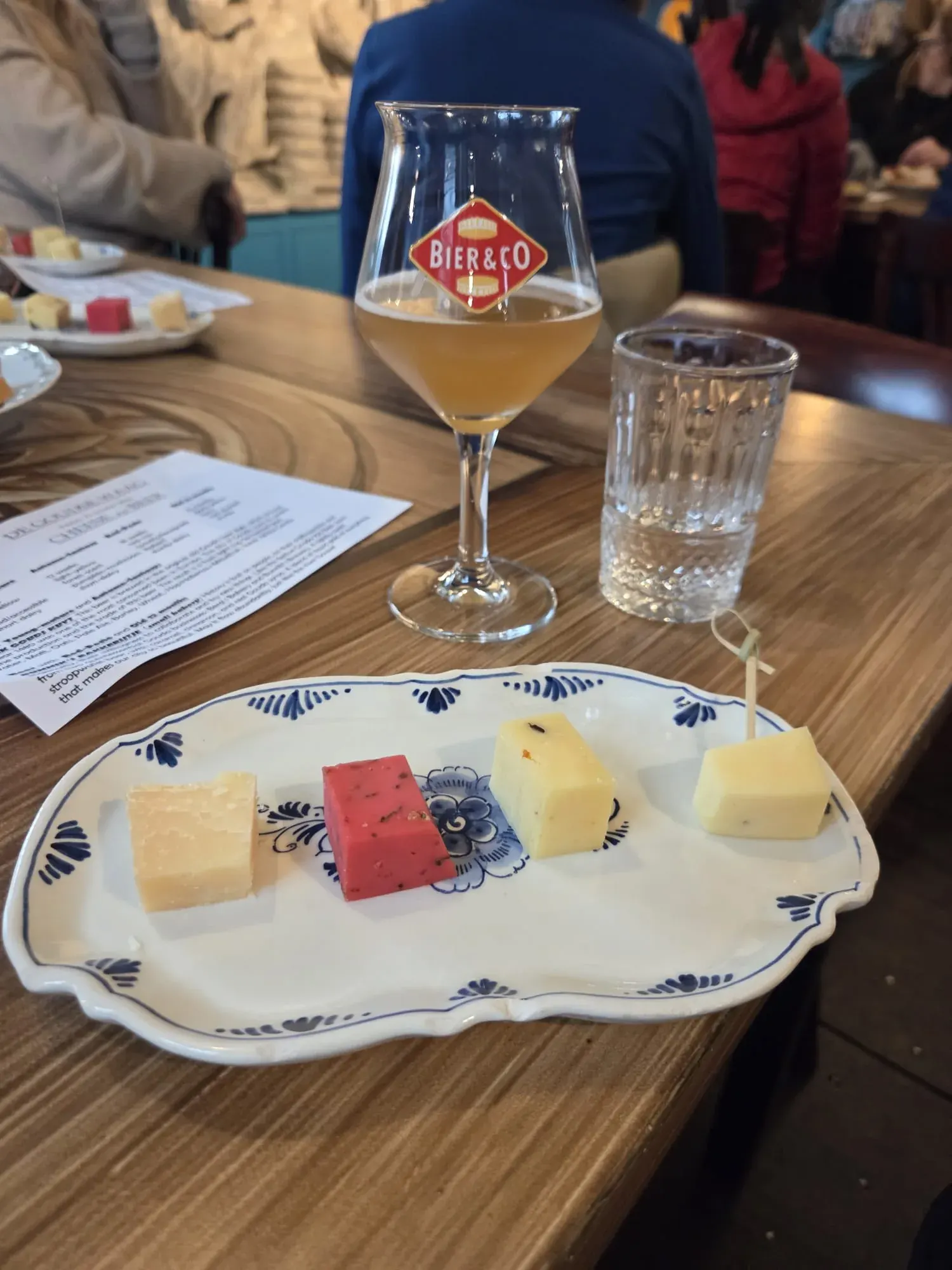 Vier Gouda-Käse auf einem Delfter-Blau-Teller mit einem Glas lokalem Bier bei der Verkostung in der Goudse Waag