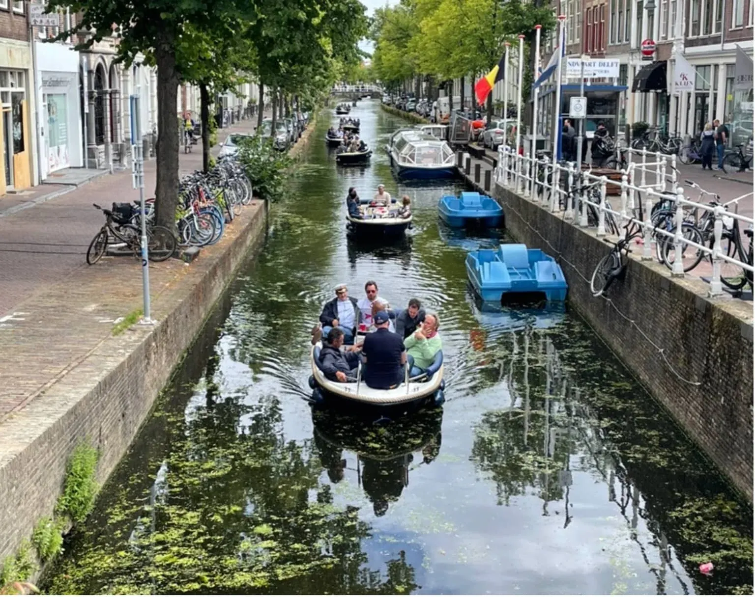A group of guests on an open canal boat, seen from a bridge above