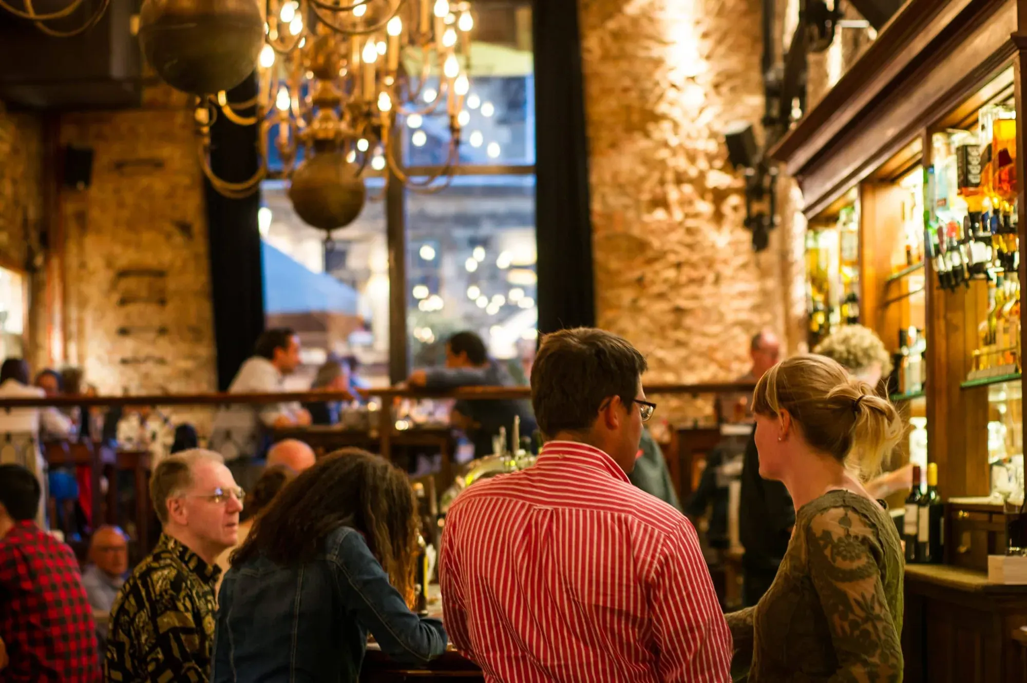The busy interior of a historic restaurant, brick walls and chandeliers