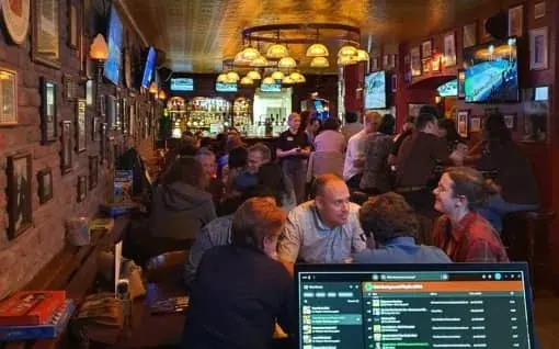 A busy cafe with a quiz scoreboard on the screen above the bar