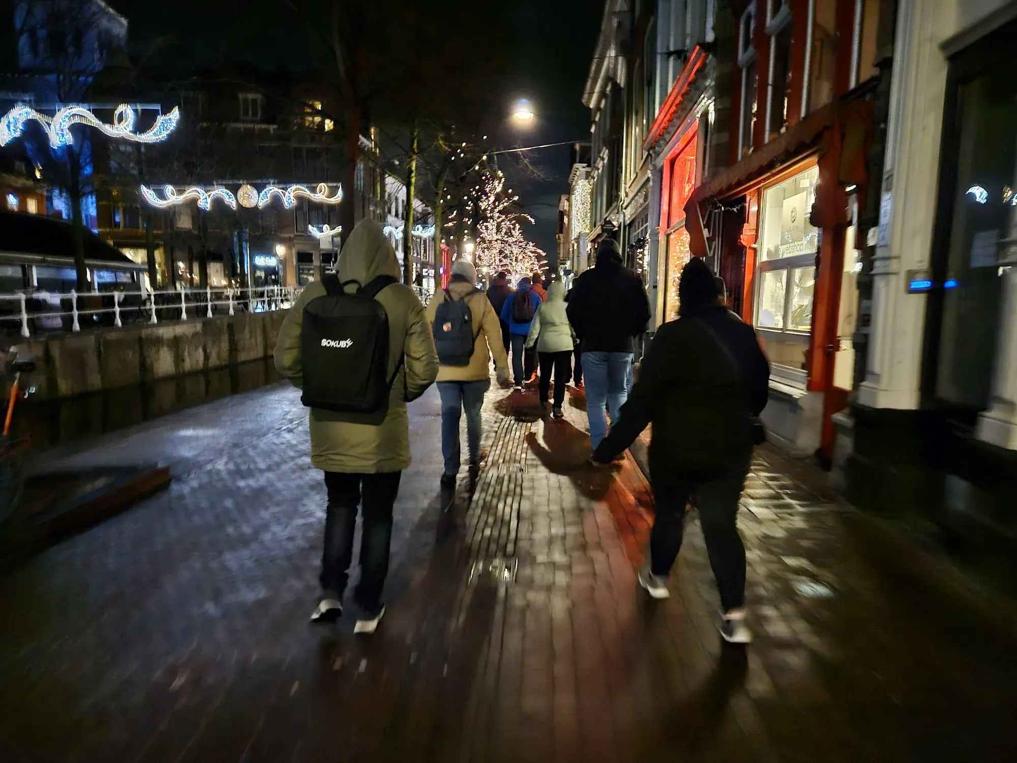 A group walking a historic shopping street at night between dinner courses, lit by street lights