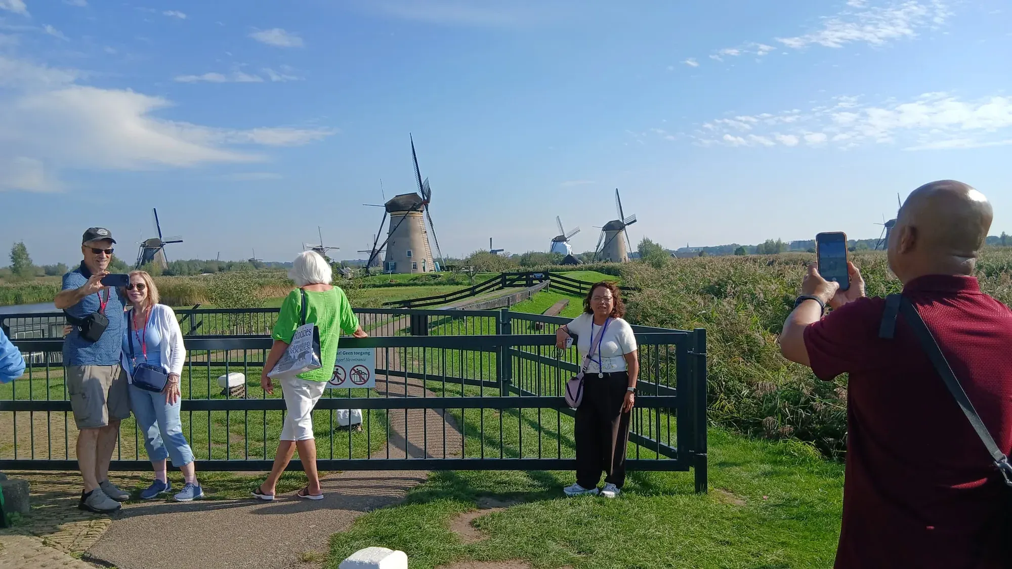 Visitors photographing the row of windmills at Kinderdijk from the dike
