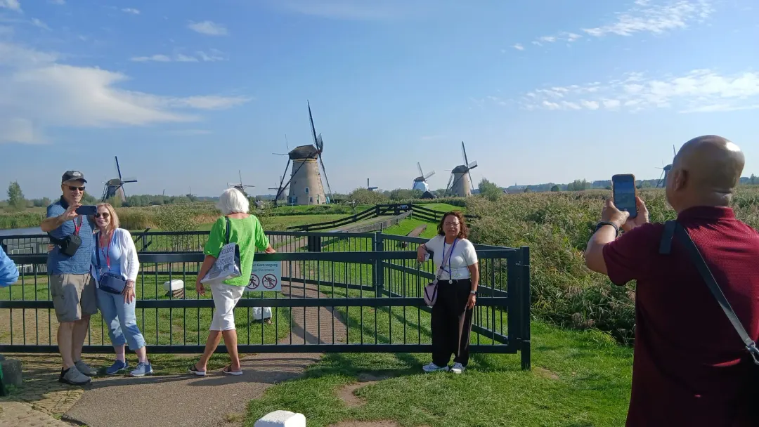 Shore excursion guests taking photos in front of the Kinderdijk windmills