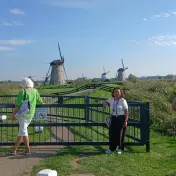 Besucher fotografieren vom Deich aus die Reihe der Windmühlen von Kinderdijk