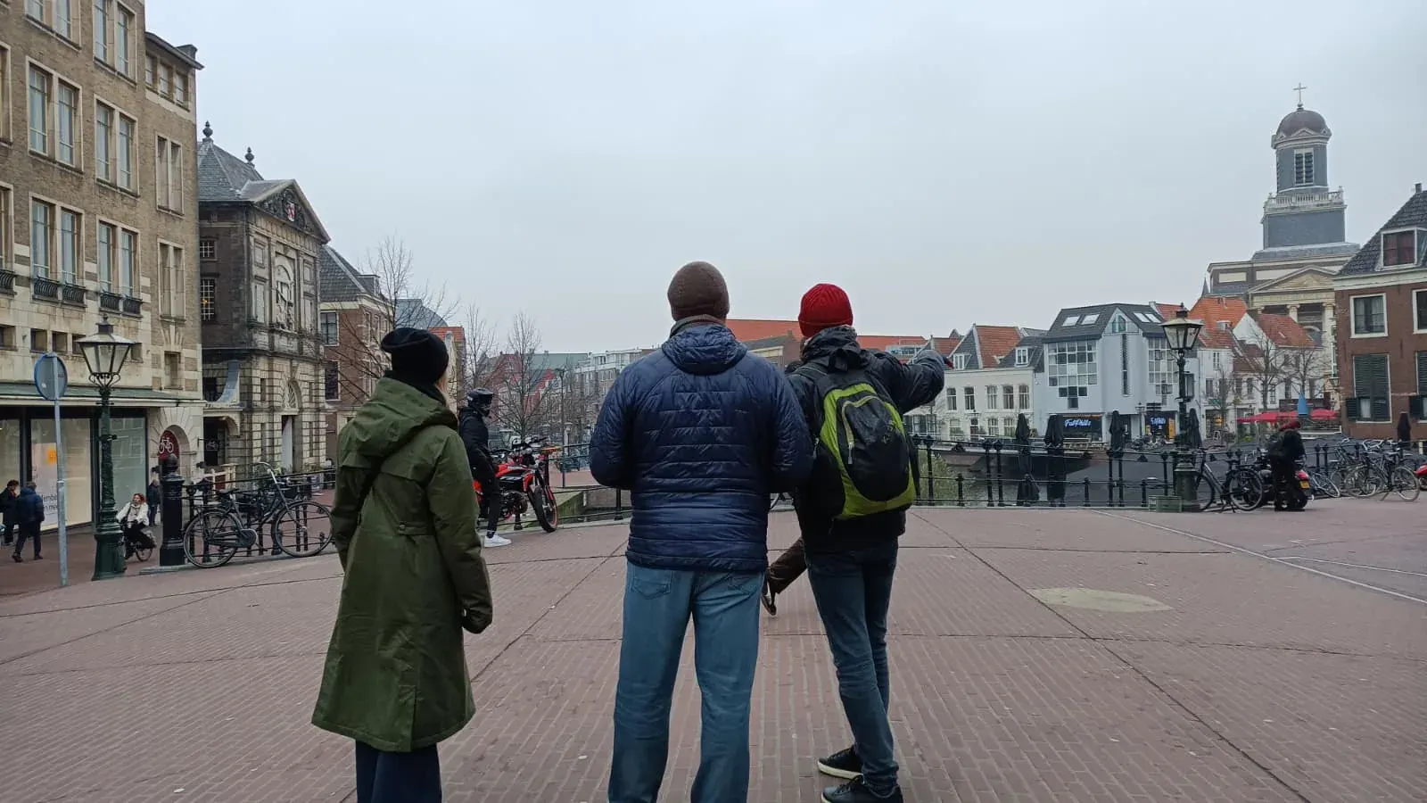 A guide and guests overlooking a Leiden canal from a bridge