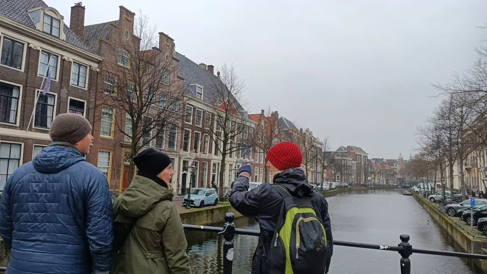 A guide and a small private tour group beside the Rapenburg canal, under the gabled houses of the old town, Leiden