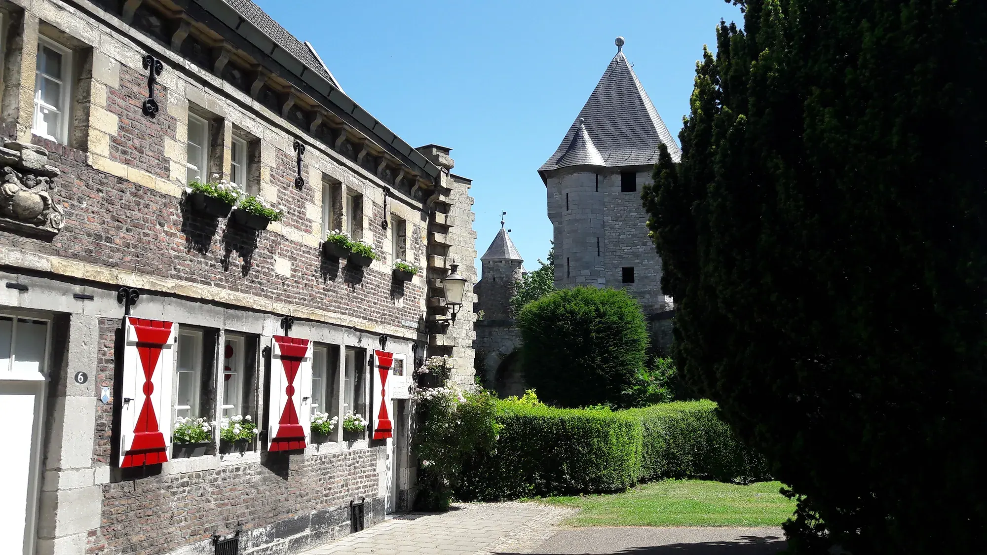 A house with bright red shutters beside a tower of the old city wall, Maastricht