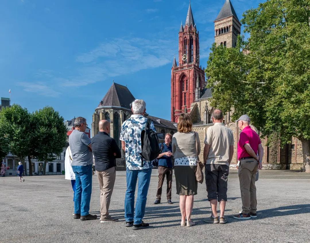 A tour group on the Vrijthof square with the red tower of the Sint-Janskerk behind, Maastricht