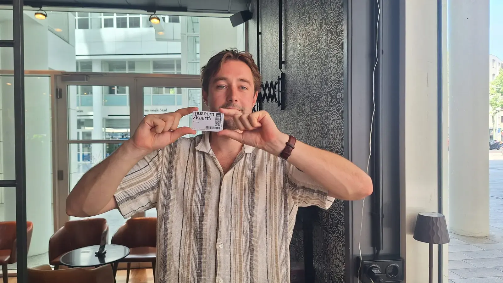 Robin holding a museum pass or museumkaart.
