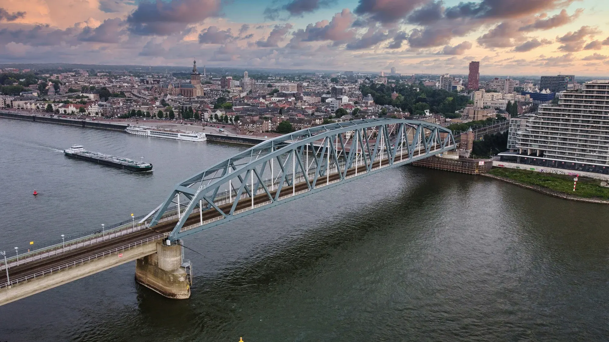 A bridge across the Waal at Nijmegen at dusk, with the city on its ridge behind