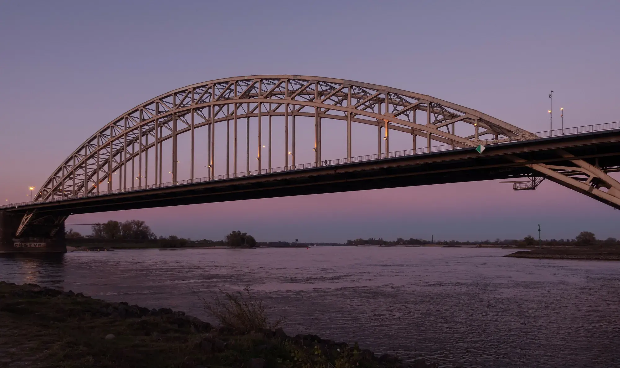 The steel arch of the Waalbrug over the river Waal at dusk