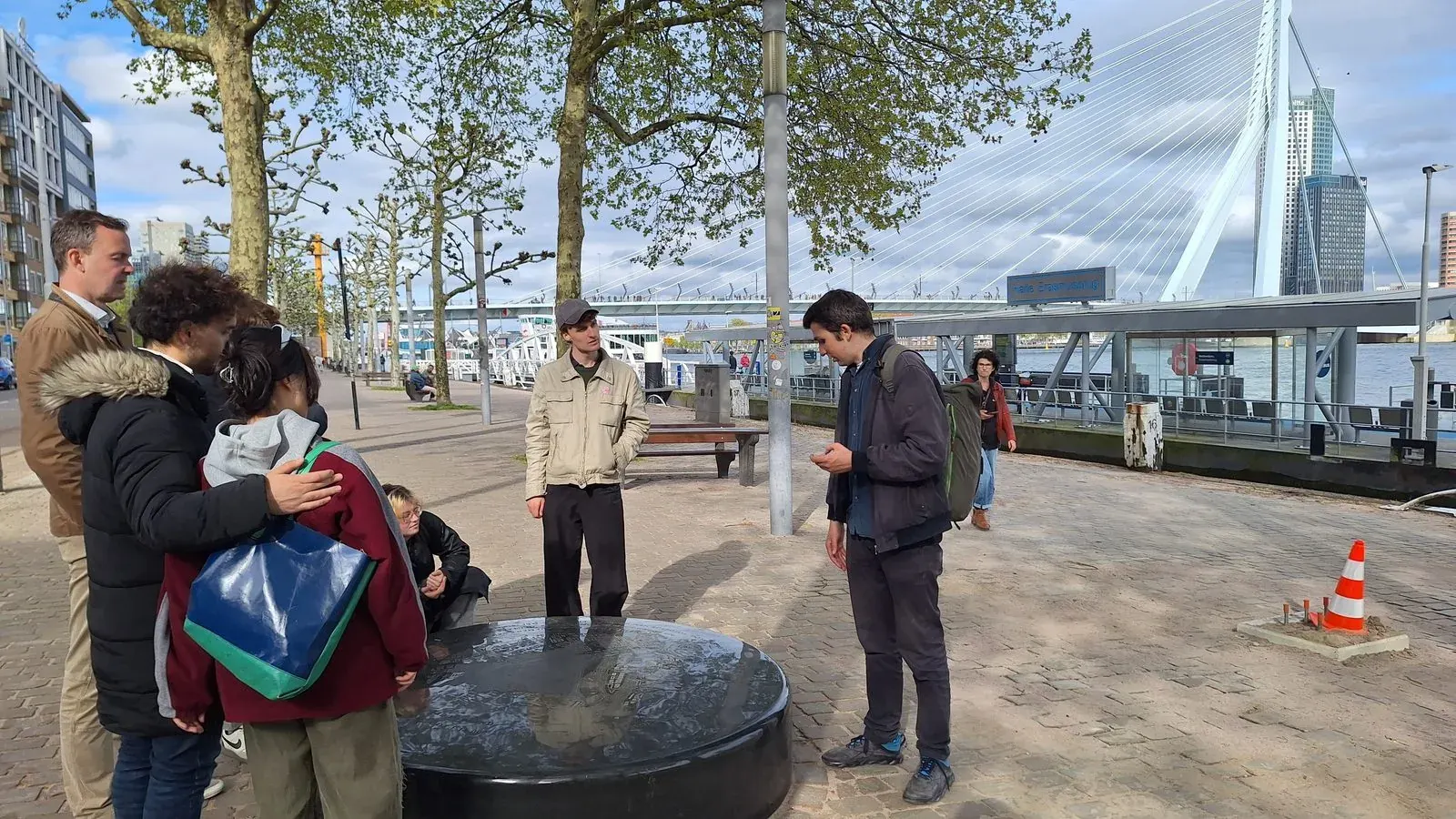Guests beside a reflecting water feature on the Boompjes waterfront, the Erasmus Bridge behind, Rotterdam