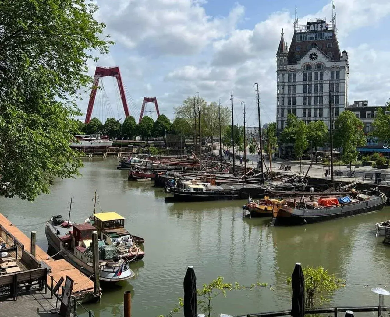 Historic ships moored in Rotterdam's Oude Haven, with the Witte Huis and the Willemsbrug behind