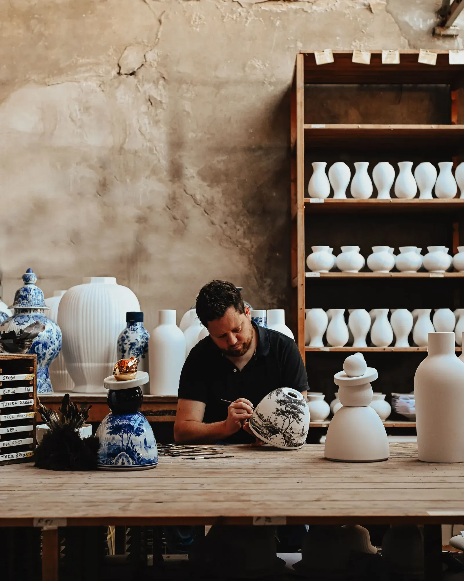 A Royal Delft artisan hand-painting Delftware in the workshop