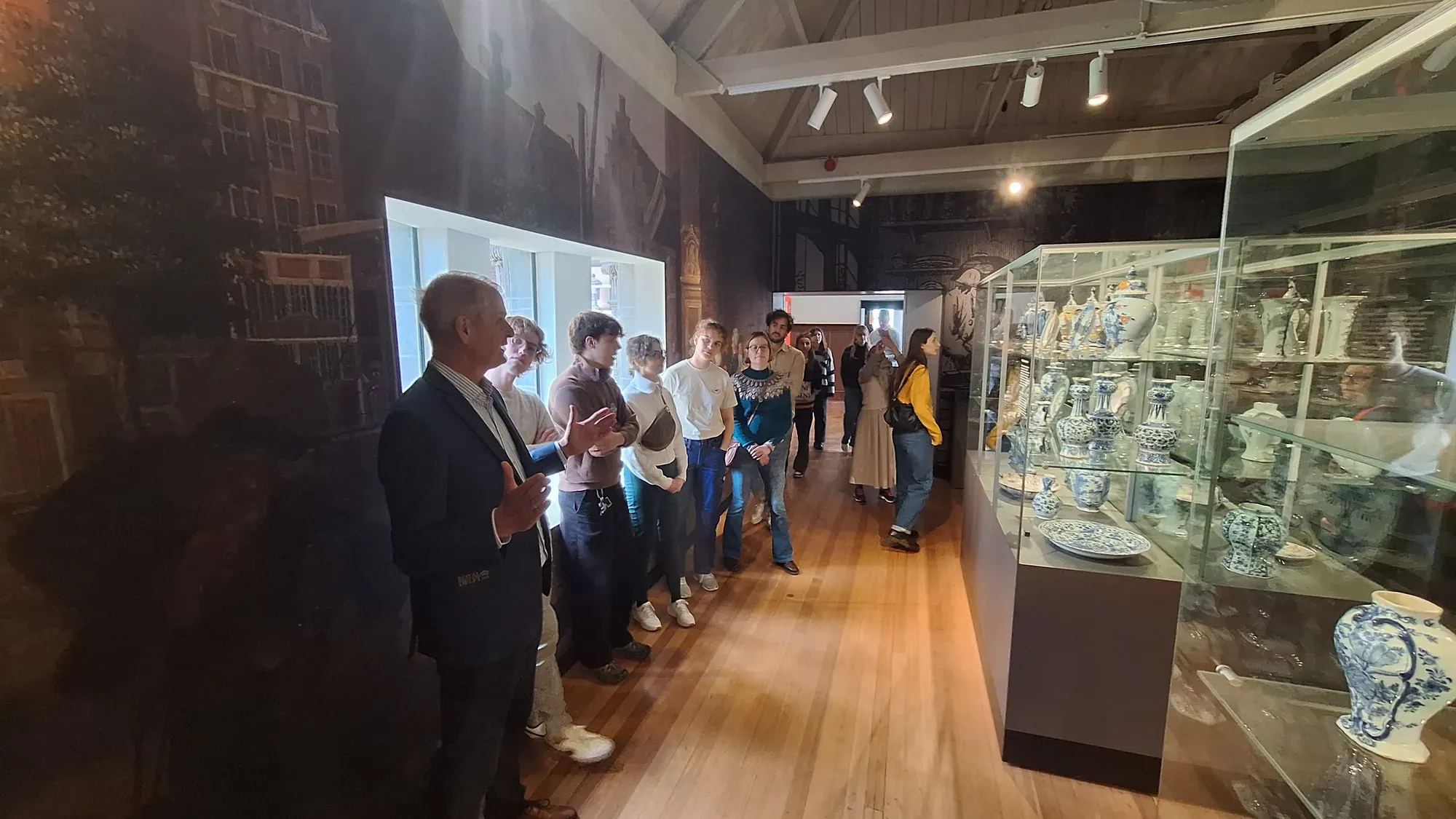 A tour group with their guide in the Royal Delft museum gallery