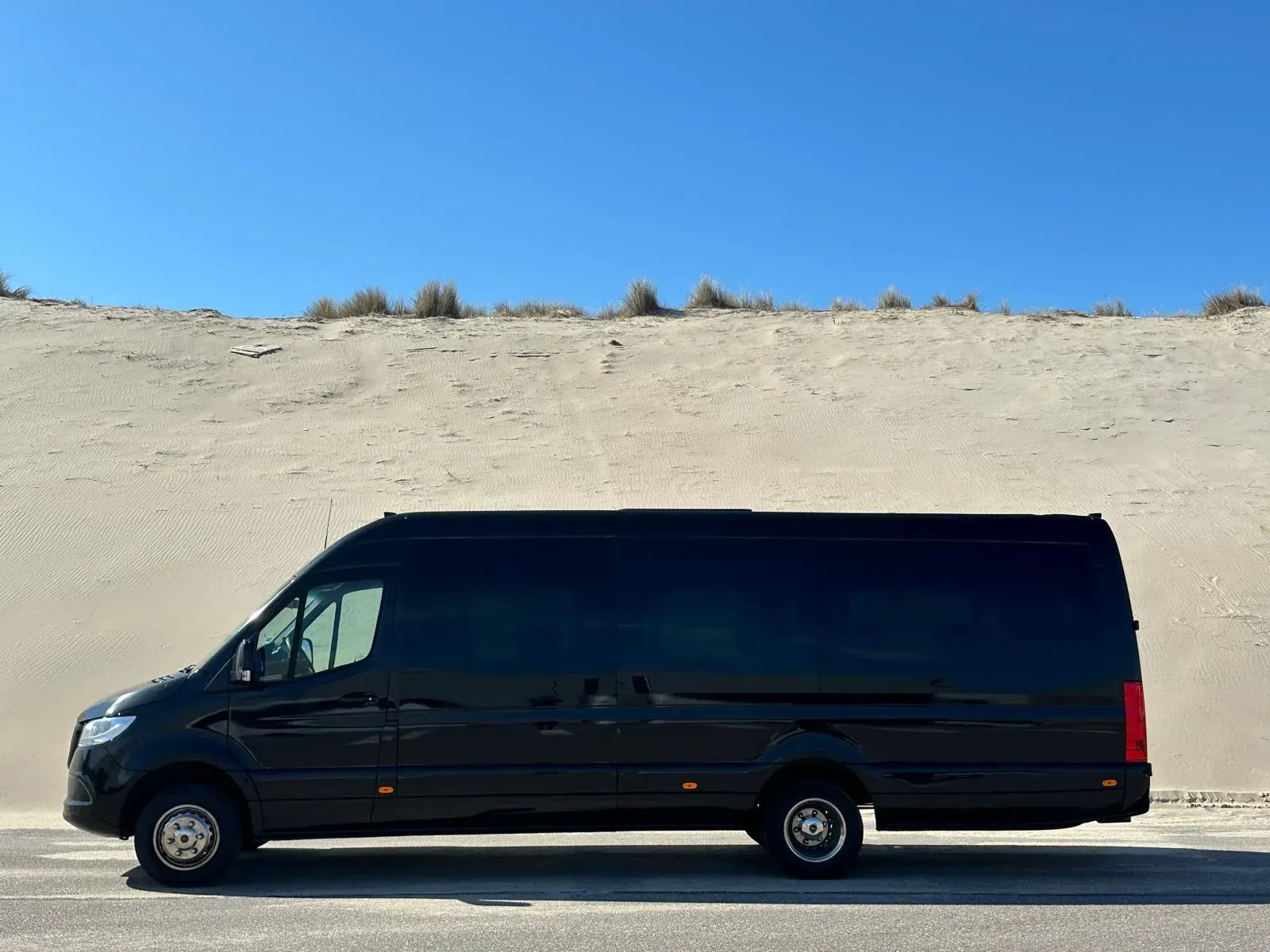The Holland City Tours minivan parked beside the coastal dunes