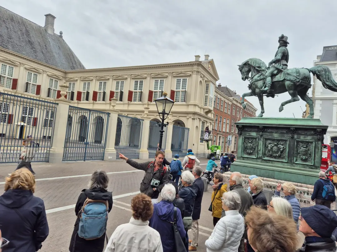 A guide talking to a large tour group beside the equestrian statue at Noordeinde Palace, The Hague