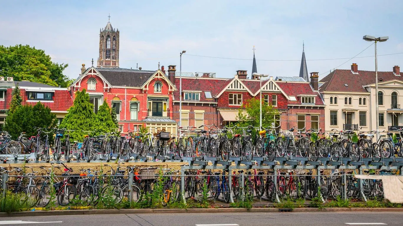Long rows of parked bicycles along a canal in Utrecht, with church spires behind