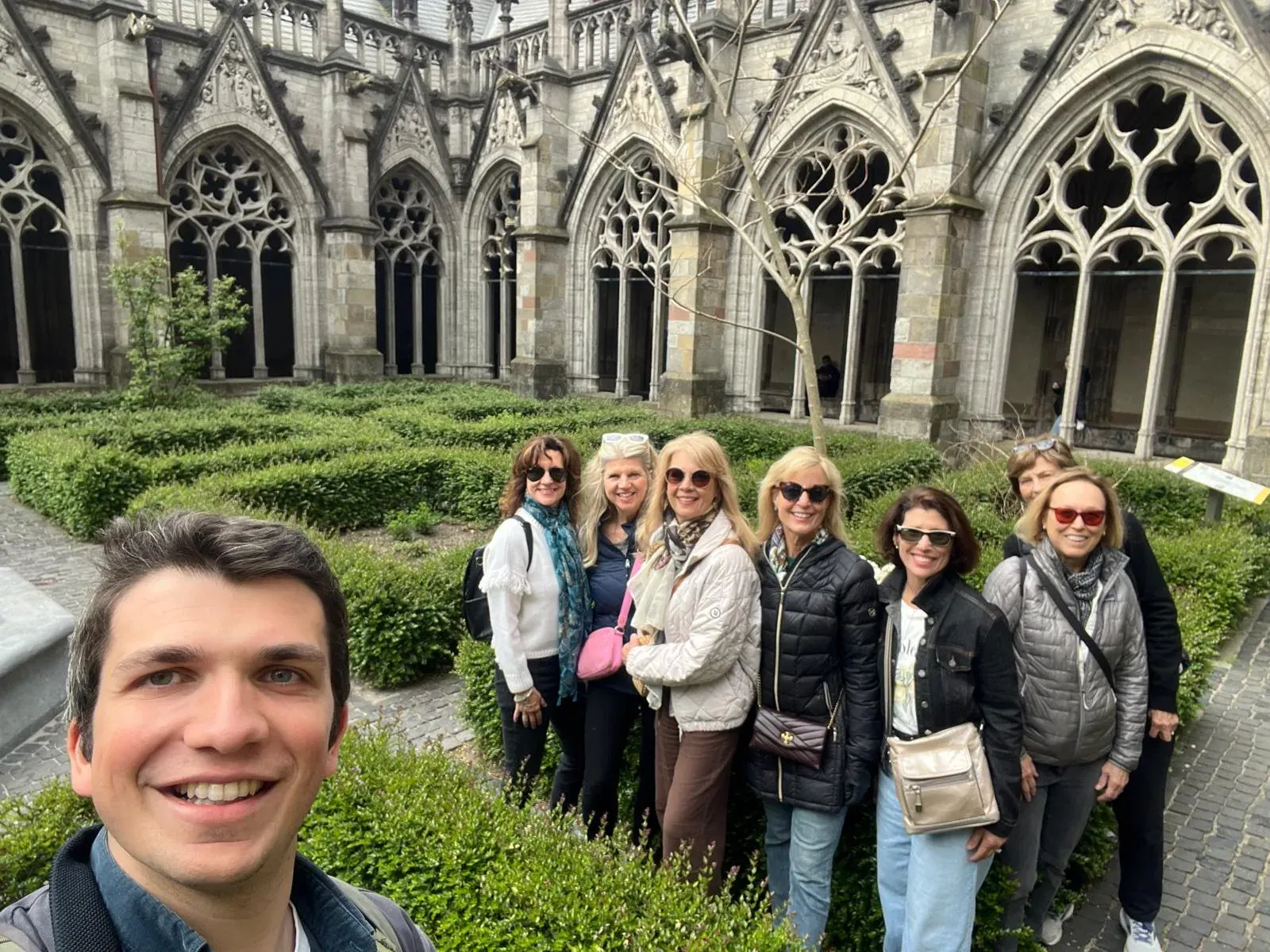 A guide and a group of guests in a Gothic cloister garden, Utrecht